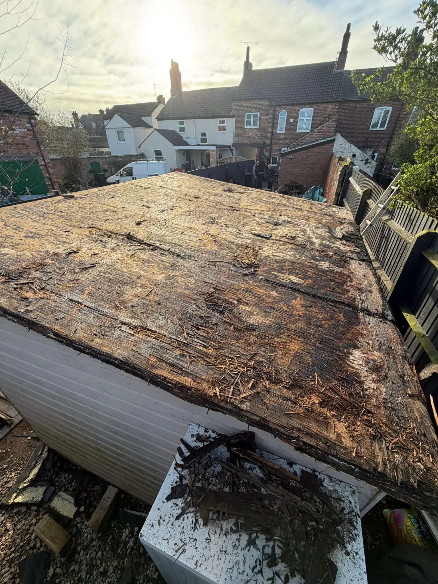 Garden shed roof with the old felt stripped off, showing the worn timber boards underneath