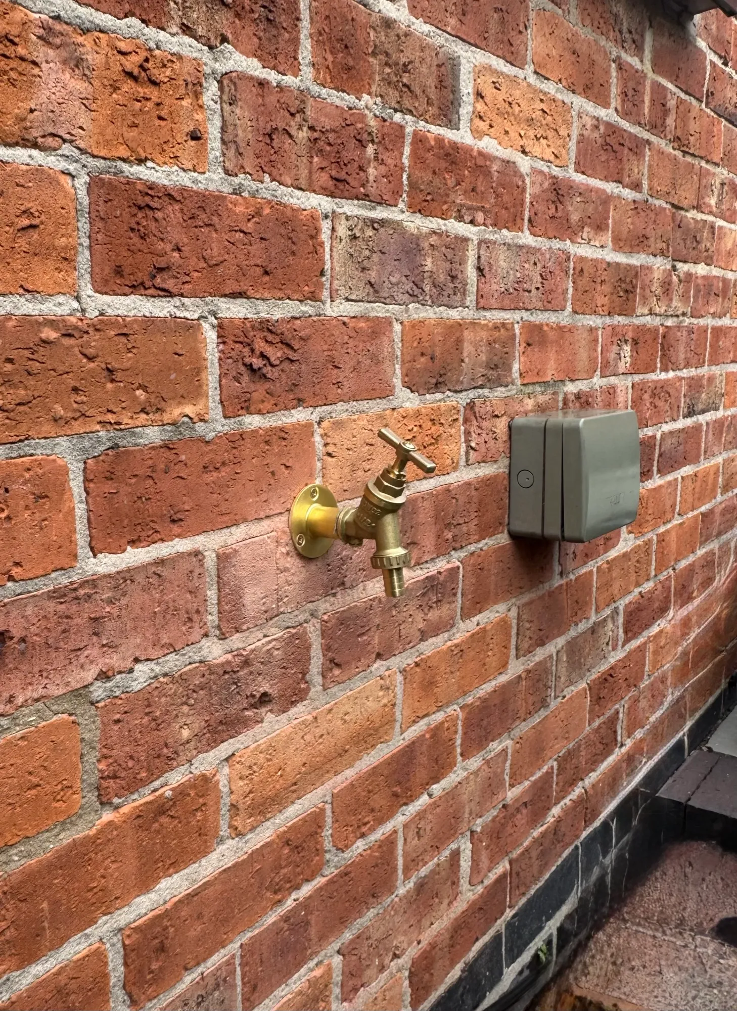 Outdoor tap fitted to an exterior brick wall