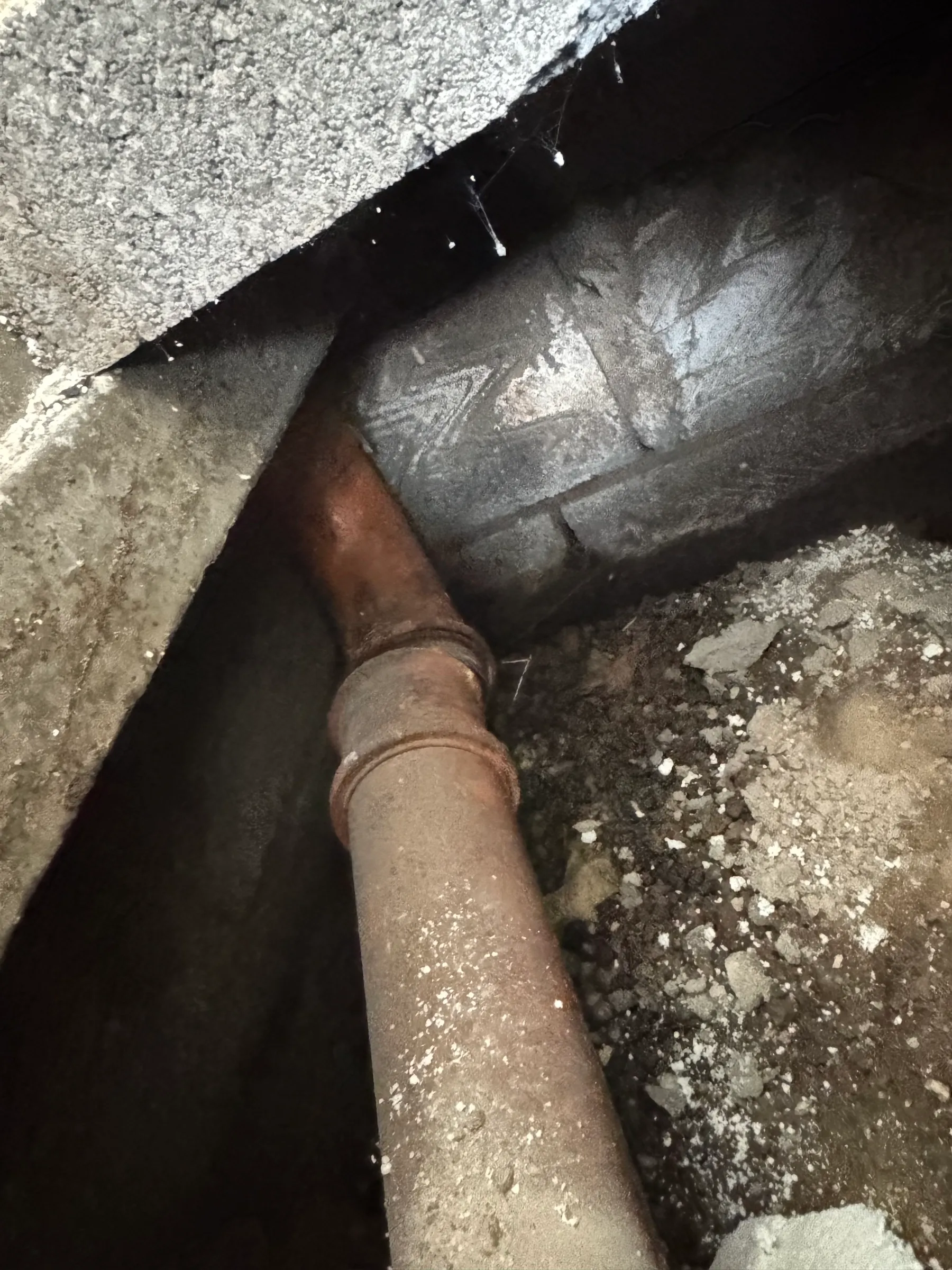 The damaged soil pipe exposed beneath the floor