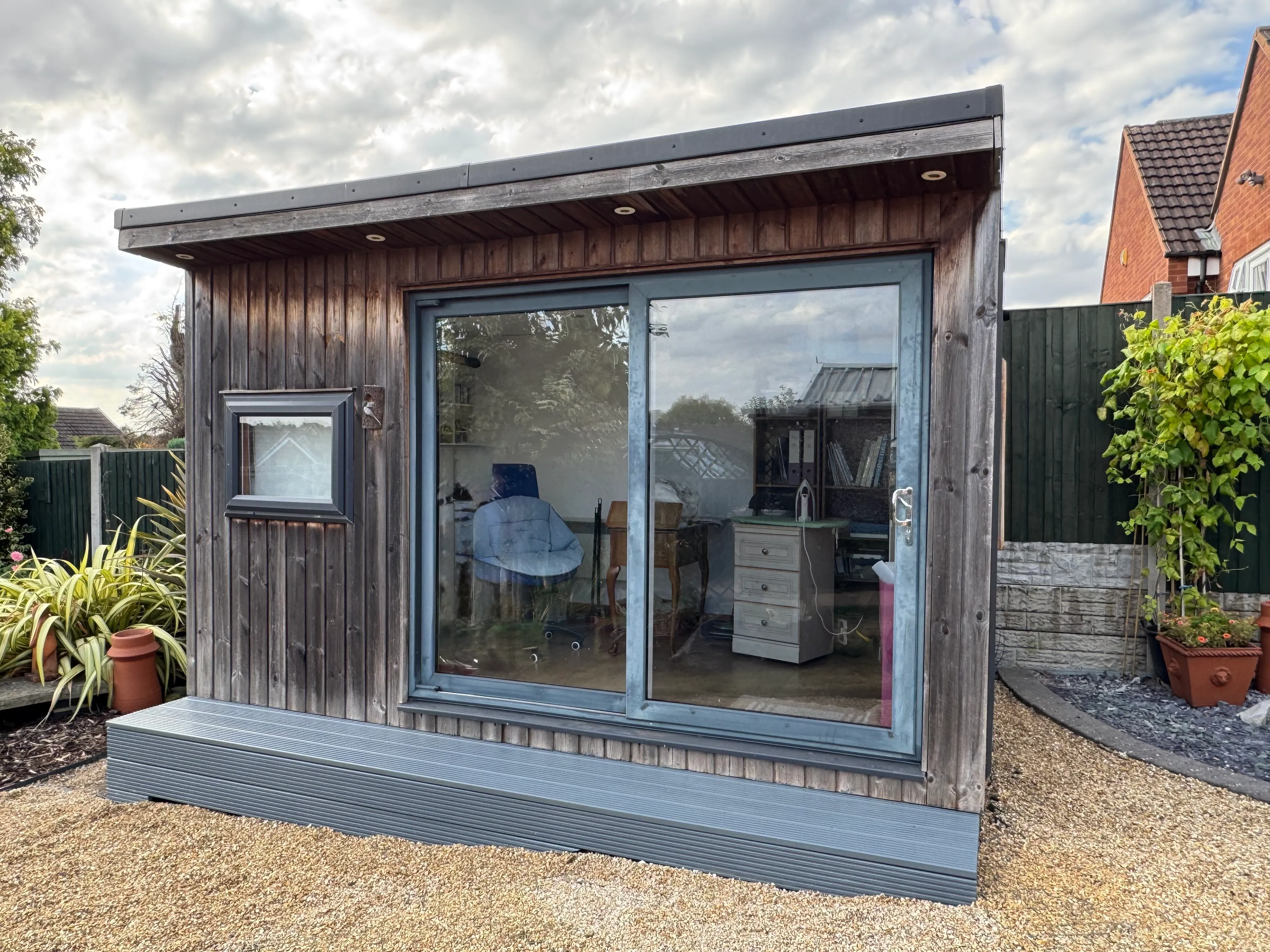 Garden room with newly laid decking running the full width of the front, painted grey