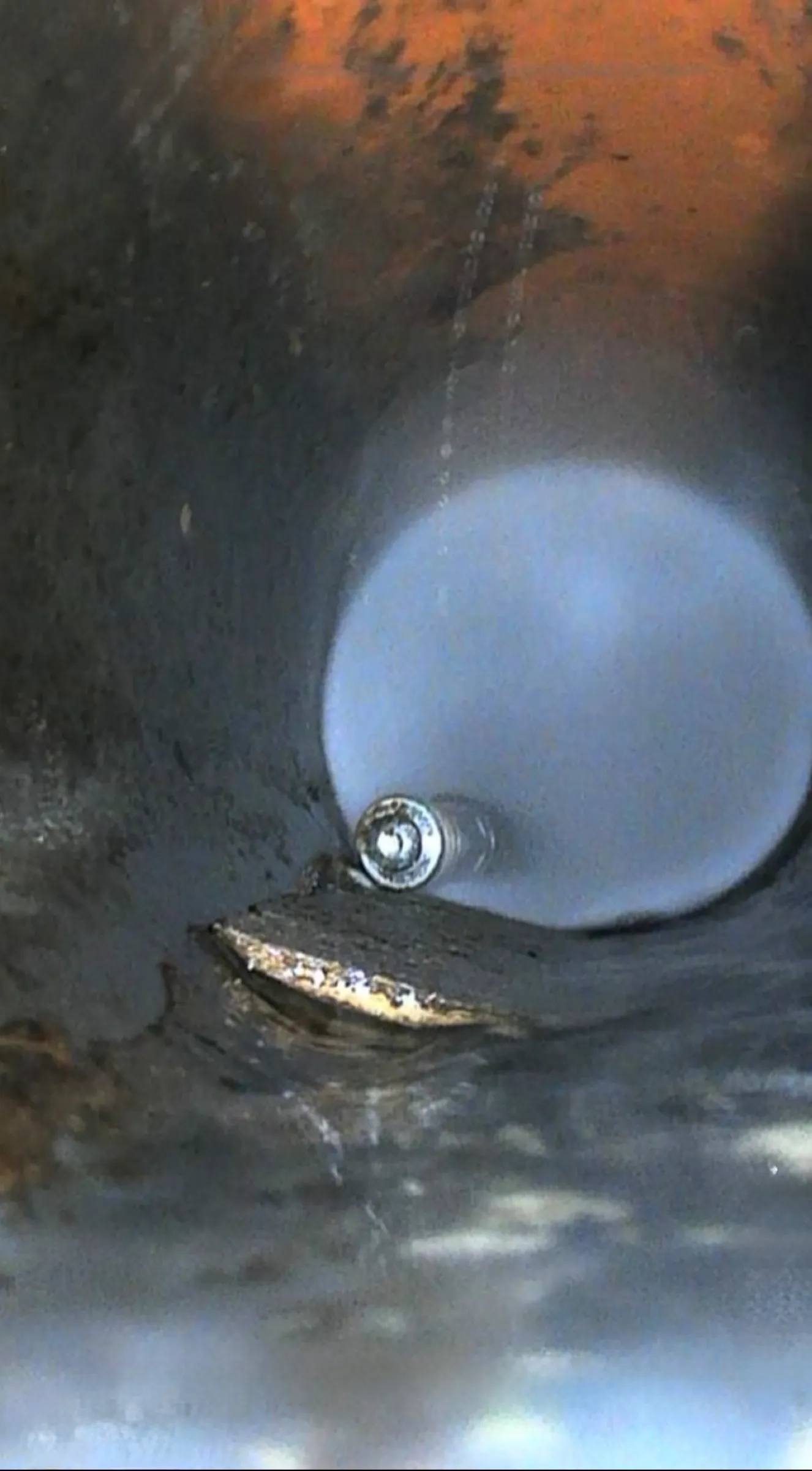 Camera view inside the drain with the jetting nozzle working and scale banked along the pipe wall